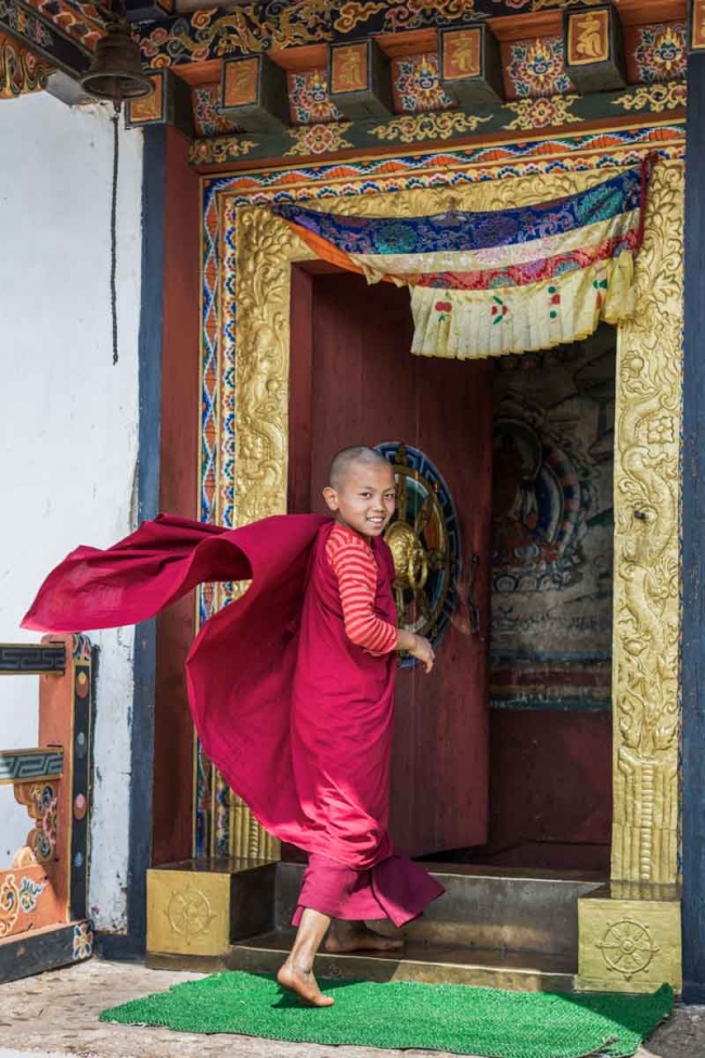 Young novice Buddhist monk entering Chimi Lhakhang (temple) near Punakha, Western Bhutan
