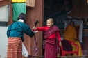 A very young monk pours holy water into the hand of a woman at Gangtey monastery, Western Bhutan