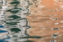 Abstract shapes in dark green, white and tan, reflected in a canal in Venice