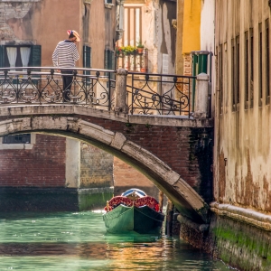 Gondolier on bridge over canal in Venice