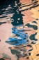 Reflection of a gondolier in a pink and gold canal in Venice