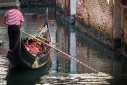 Gondola and gondolier with red stripes on canal in Venice