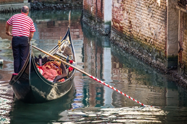 Gondola and gondolier on canal in Venice, horizontal